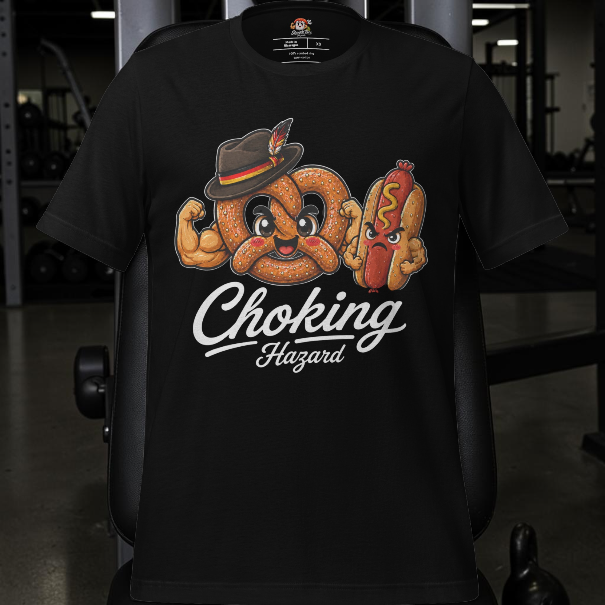 Show off your playful side with the Choking Hazard Tee – Germany Edition by Straight Face Originals! This black Bella + Canvas 3001 t-shirt features a cartoon pretzel with muscles and a hat, facing off against a surprised hot dog, all showcased on a gym chair. The bold “Choking Hazard” text beneath makes it the perfect dating profile shirt for those who want to mix humor and style.